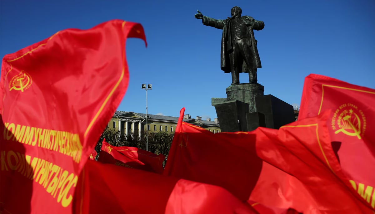 Flags flutter in front of a monument to Soviet state founder Vladimir Lenin during a rally held by Russian Communist Party supporters to mark the Red October revolutions centenary in St. Petersburg. — Reuters/File