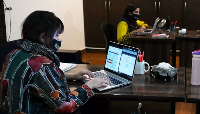 In this undated photo, two women are using their laptops in an office. — AFP