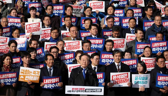 South Koreas main opposition Democratic Party leader Lee Jae-myung looks on as people hold placards that read Step down President Yoon Suk Yeol and Investigate his act of rebellion immediately, at a rally to condemn South Korean presidents surprise declarations of the martial law and to call for his resignation, at the national assembly in Seoul, South Korea, December 4, 2024. — Reuters