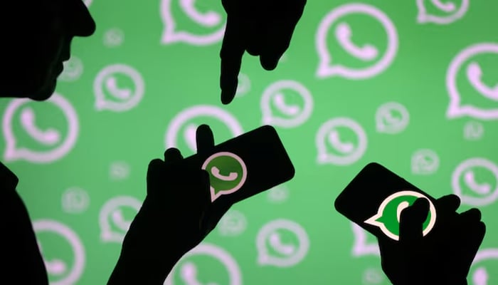 Men pose with smartphones in front of displayed Whatsapp logo in this illustration September 14, 2017.