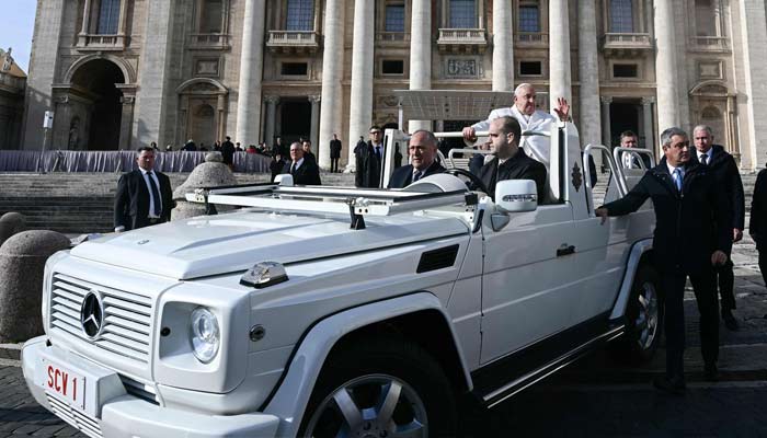 Pope Francis waves to the crowd from his previous popemobile — also made by Mercedes — during the weekly general audience in St Peters Square at the Vatican on December 4, 2024. — AFP