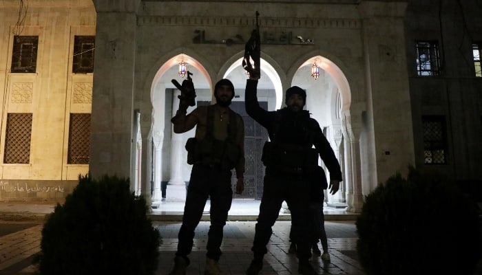 Rebel fighters hold weapons in front of Hama governors building as they gather after Syrian rebels captured the city during their advance across northern Syria, in Hama, Syria, on December 5, 2024. —Reuters