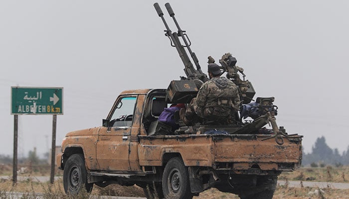 Ein Rebellenkämpfer sitzt auf dem Rücksitz eines Fahrzeugs im ländlichen Homs, nachdem die syrischen Rebellen am Samstag ihren blitzschnellen Vormarsch vorangetrieben hatten und sagten, sie hätten den größten Teil des Südens erobert, während Regierungstruppen sich eingruben, um die wichtige Innenstadt von Homs zu verteidigen und zu retten 24-jährige Herrschaft von Präsident Baschar al-Assad in Syrien, 7. Dezember 2024. – Reuters