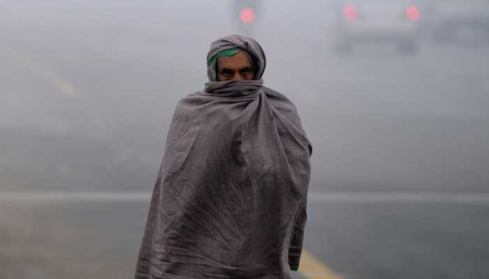 A man covering himself up with warm clothes due to severe cold. — AFP/File