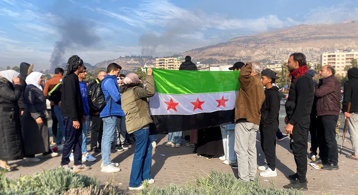 Menschen halten die Flagge der syrischen Opposition hoch, während sie in Damaskus nach dem Ende der Herrschaft von Präsident Baschar al-Assad nach der Offensive der Rebellen feiern. — Reuters