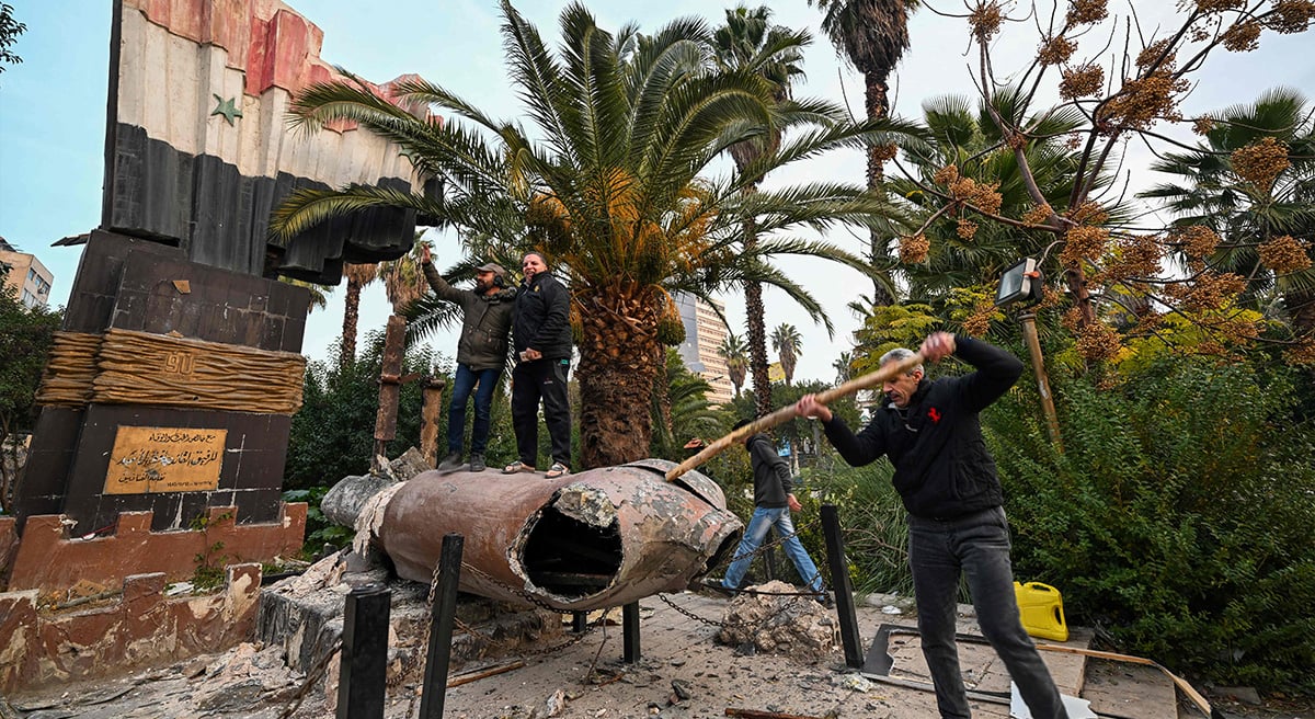 Menschen stehen am 8. Dezember 2024 in Damaskus auf einer umgestürzten Statue des verstorbenen syrischen Präsidenten Hafez al-Assad, nach dem Ende der Herrschaft von Präsident Baschar al-Assad nach einer Rebellenoffensive. — AFP