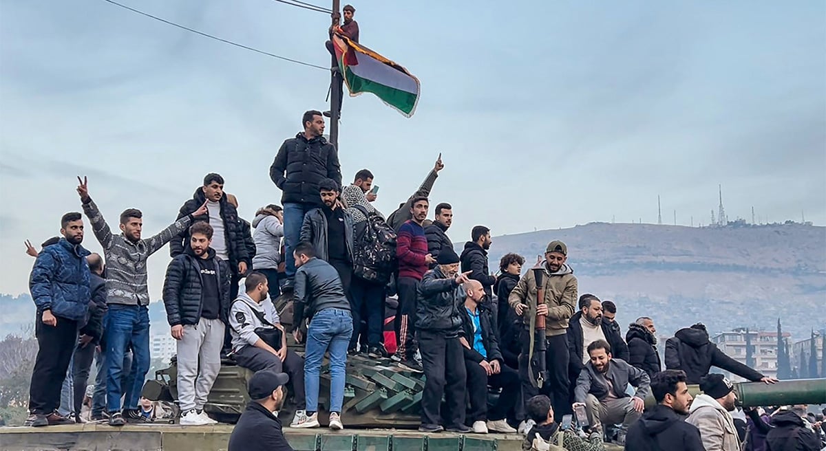 This screenshot taken from AFPTV shows people sitting on a tank as they gather at Umayyad Square in Damascus on December 8, 2024, after end of President Bashar al-Assads rule following rebel offensive. — AFP