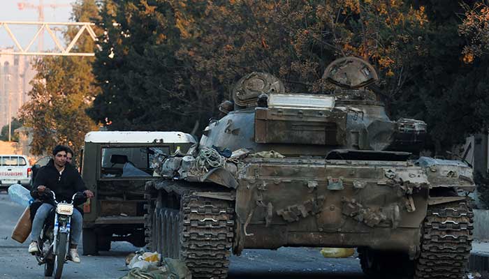 Menschen auf einem Fahrrad fahren an einem Panzer der syrischen Armee vorbei, nachdem syrische Rebellen bekannt gegeben hatten, dass sie Syriens Bashar al-Assad gestürzt haben, in Damaskus, Syrien, 8. Dezember 2024. – Reuters