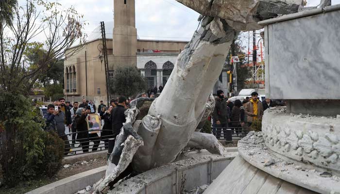 People stand near a damaged statue of former Syrian president Hafez al-Assad after Syrian rebels announced that they have ousted President Bashar al-Assad, in Qamishli, Syria December 8, 2024. — Reuters