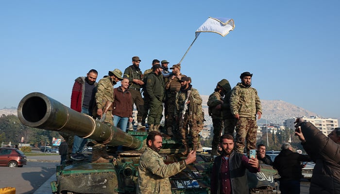 Rebel fighters stand on a tank, after rebels seized the capital and ousted President Bashar al-Assad, in Damascus, Syria, December 9, 2024. — Reuters