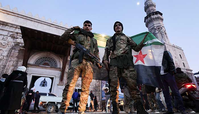 Rebel fighters pose as they hold a Syrian opposition flag at the Umayyad Mosque in Damascus, Syria on December 9, 2024. — Reuters