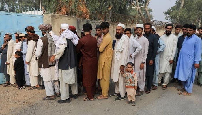 Afghan refugee men stand in queue for documentation outside the United Nations High Commissioner for Refugees (UNHCR) repatriation centres in Azakhel town in Nowshera, Pakistan, October 30. — Reuters