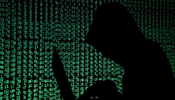 A hooded man holds a laptop computer as cyber code is projected on him in this illustration picture taken on May 13, 2017. — Reuters