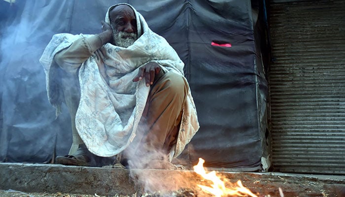 Representational image of an old man sitting near fire to keep warm in cold weather at Hashtnagri bazaar, Peshaawar, on December 10, 2024. — INP