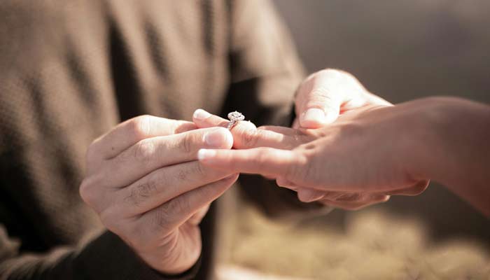 A representational image shows a man putting a ring on a womans finger. — Unsplash