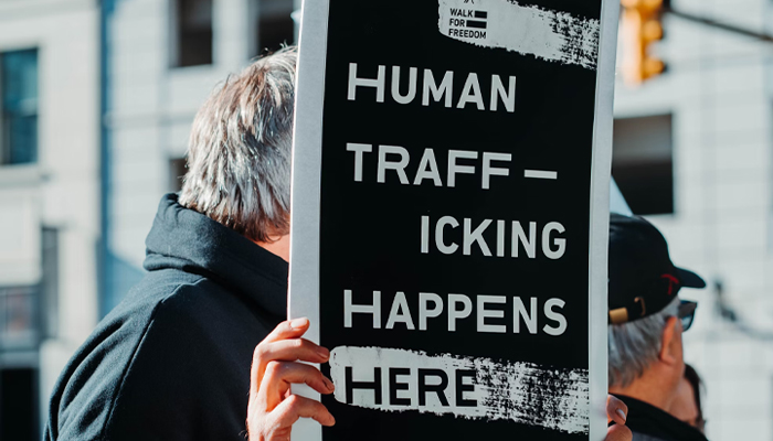 A man raises a placard during a protest against human trafficking. — Unsplash/file