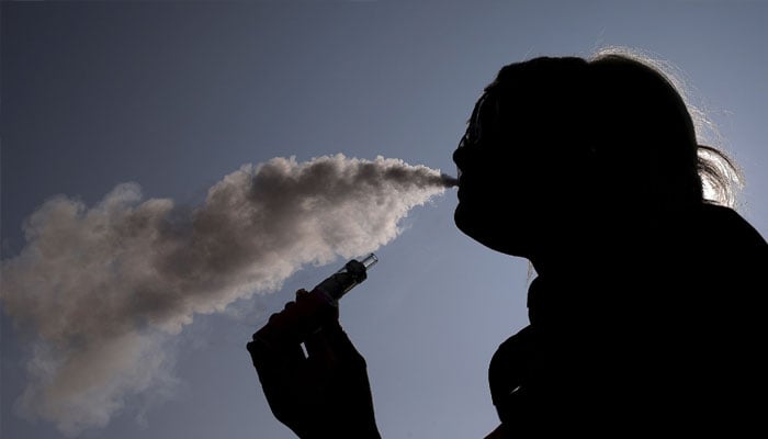 A woman exhales vapour from an e-cigarette outside the offices of British e-cigarette manufacturer Totally Wicked in Blackburn, northern England March 19, 2015. — Reuters