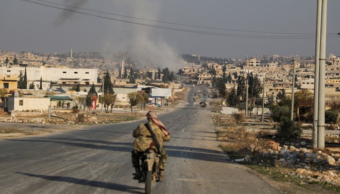 Smoke rises as a member of the rebels led by the Hayat Tahrir al-Sham drives on a motorbike in al-Rashideen, Aleppo province, Syria November 29, 2024. — Reuters