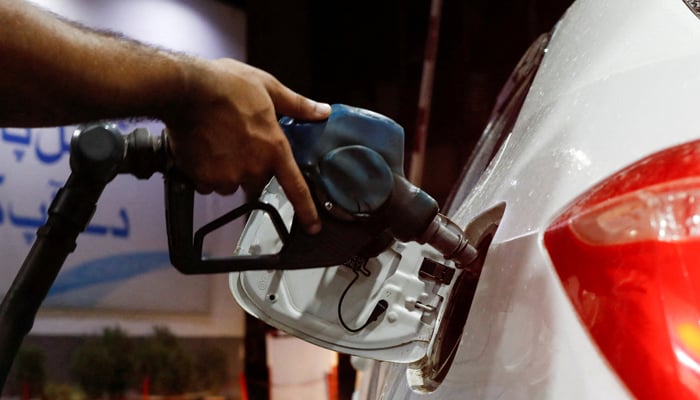 A worker holds a fuel nozzle to fills fuel in a car at petrol station in Karachi, September 16, 2023. — Reuters