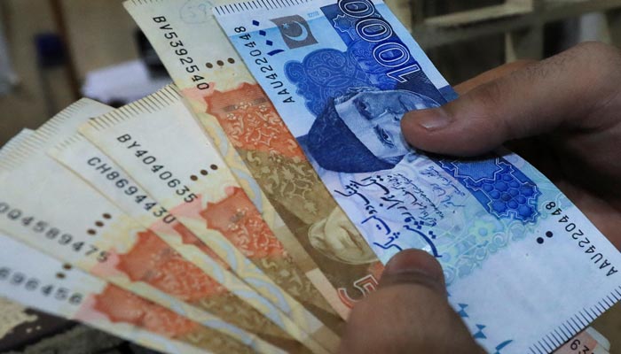 A man counts Pakistani rupee notes at a currency exchange shop in Peshawar, September 12, 2023. — Reuters