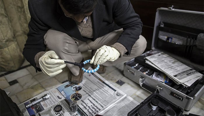 A member of the crime scene investigation unit collects fingerprints at a home that has been robbed in Lahore January 13, 2015. — Reuters