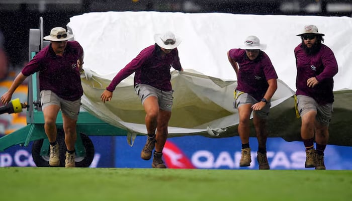 Ground staff cover the ground during a rain delay as play of the third Test of the Border-Gavaskar Trophy between India and Australia is suspended at the Brisbane Cricket Ground, Brisbane, Australia on December 14, 2024. — Reuters