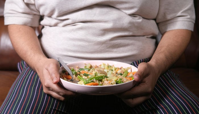 A representational image shows a person holding a plate of salad in their hands. — Pexels