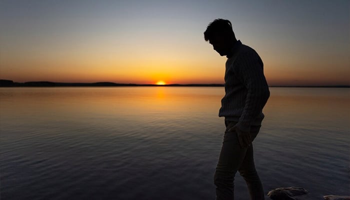 Representational photo shows a person walking near lake during sunset. — Freepik