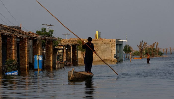 A man rows his boat as he passes through flooded market, following rains and floods during the monsoon season in Bajara village, at the banks of Manchar lake, in Sehwan, Pakistan September 6, 2022