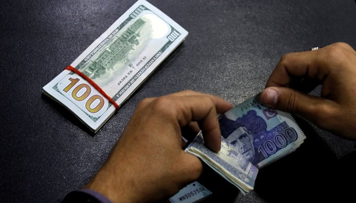 A currency trader counts Pakistani Rupee notes as he prepares an exchange of US dollars in Islamabad, December 11, 2017. — Reuters