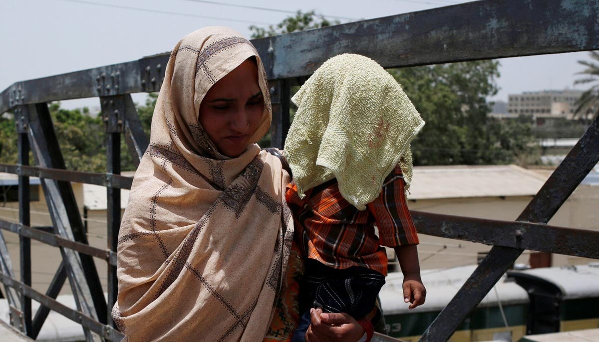 A mother holds her child, covered with a towel to avoid sunlight, during a heatwave in Karachi on May 21, 2018. — Reuters