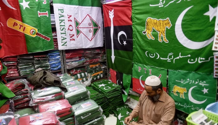 A shopkeeper arranges flags of political parties at his shop ahead of the upcoming general elections in Karachi, Pakistan, on January 3, 2024. — AFP