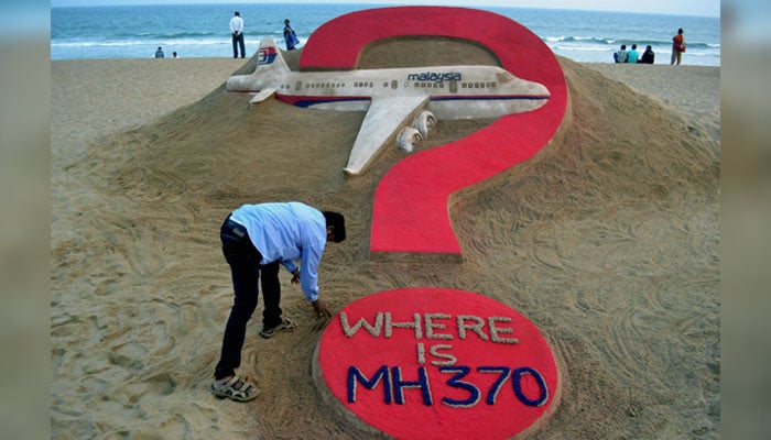 Indian sand artist Sudarsan Pattnaik creates a sand sculpture of the missing Malaysia Airlines flight MH370 on Puri beach in eastern Odisha, India on March 7, 2015. — AFP