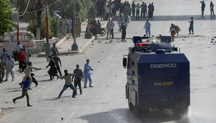 Supporter of former prime minister Imran Khan throw stones at a police vehicle during a protest after Khans arrest, in Karachi, on May 9, 2023. — Reuters