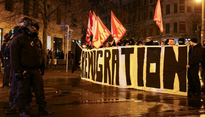 Police officers line up as far-right demonstrators hold a sign and flags during a protest after a car drove into a crowd at a Christmas market, in Magdeburg, Germany December 21, 2024. — Reuters