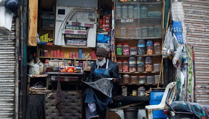 Representational image of a shopkeeper reading newspaper while selling betel leaves, cigarettes and candies in Karachi. — Reuters/File