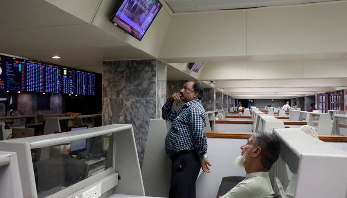 Stock brokers monitor new on television screen at a booth, during a trading session at the Pakistan Stock Exchange, in Karachi, July 3, 2023. — Reuters