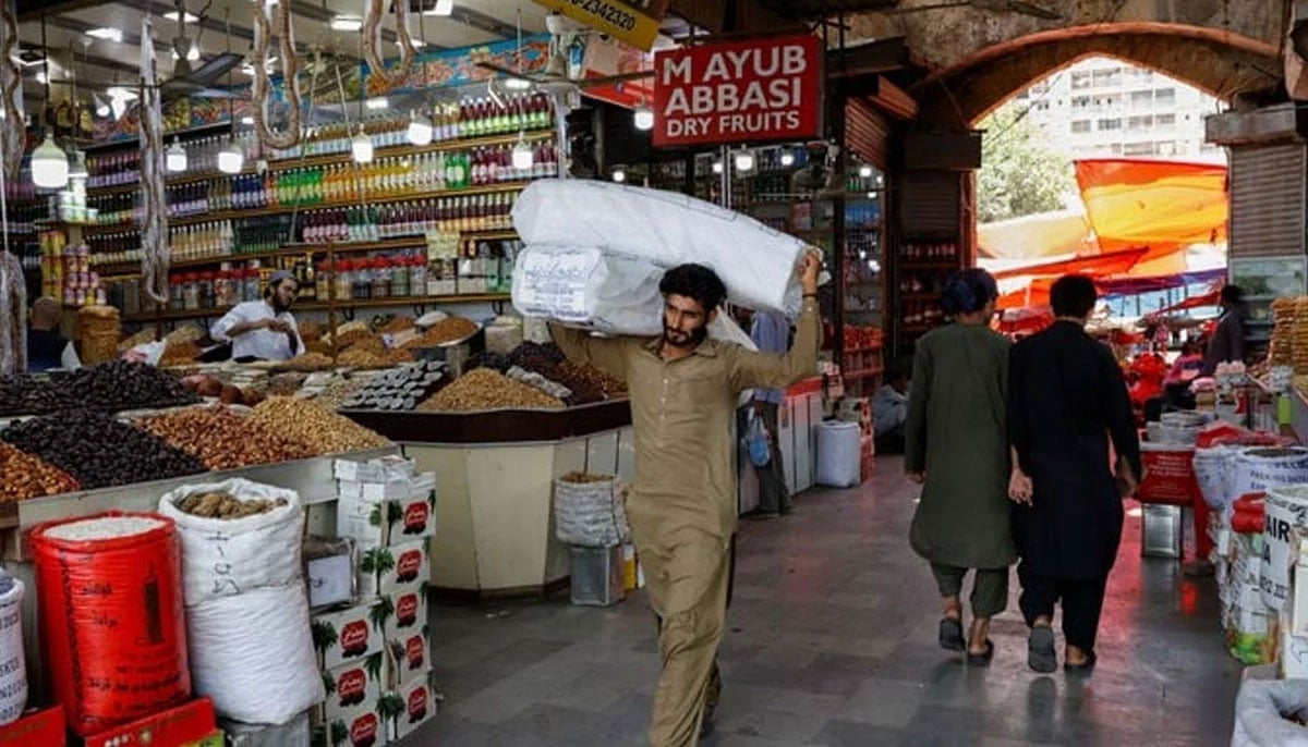 A man walks with sacks of supplies on his shoulder to deliver to a nearby shop at a market in Karachi, June 11, 2024. — Reuters