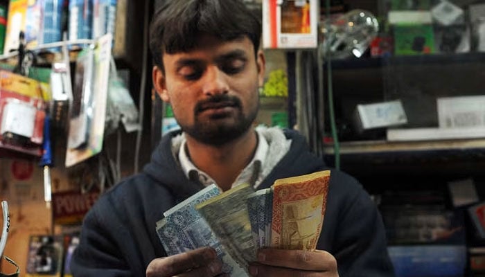 A representational image of a Pakistani shopkeeper counting money at a store in Islamabad. — AFP/File