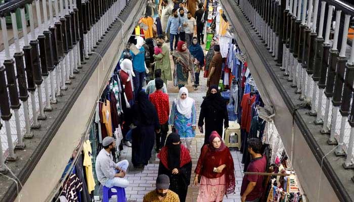 People walk as they shop in a market in Karachi on April 19, 2023. — Reuters