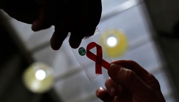 This representational image shows a nurse (left) handing out a red ribbon to a woman at the entrance of Emilio Ribas Hospital, in Sao Paulo December 1, 2014. — Reuters