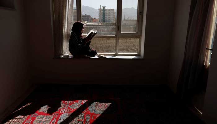 Hawa, 20, a third-year Russian literature student at the Burhanuddin Rabbani University (which was renamed by the Taliban to Kabul Education University), reads a book as she sits on a windowsill at her home in Kabul, Afghanistan, October 23, 2021. — Reuters