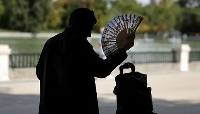 A man uses a hand fan in a park in central Madrid during a heatwave, on August 2, 2022. — AFP/File