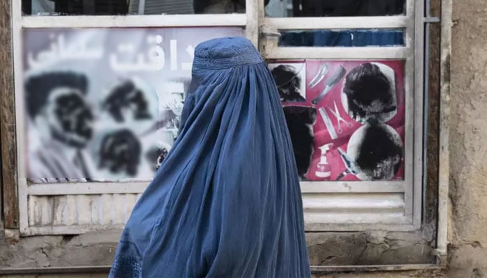 An Afghan woman stands by a window in Kabul on January 31, 2024. — AFP