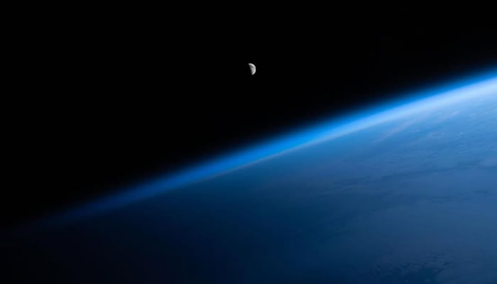 Seen from the International Space Station (ISS), the moon appears partially lit with the Earth appears blue with faint white clouds in the atmosphere, stretching from the bottom left to the top right of the image. — Instagram/@Nasa/File