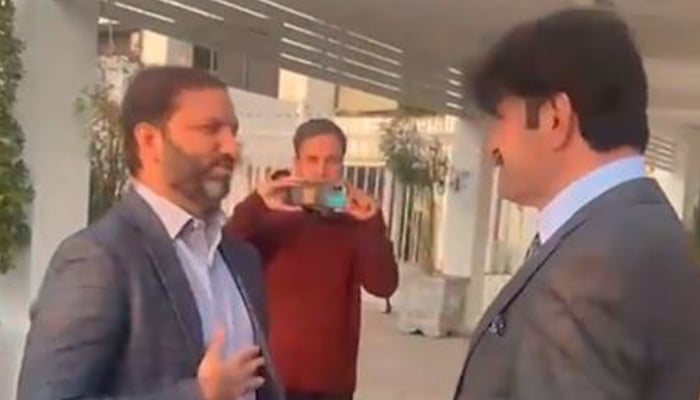 PML-N leader Afnan Ullah Khan (L) gestures while meeting PTIs Sher Afzal Marwat outside parliament House on January 6, 2025. — Screengrab via Geo News