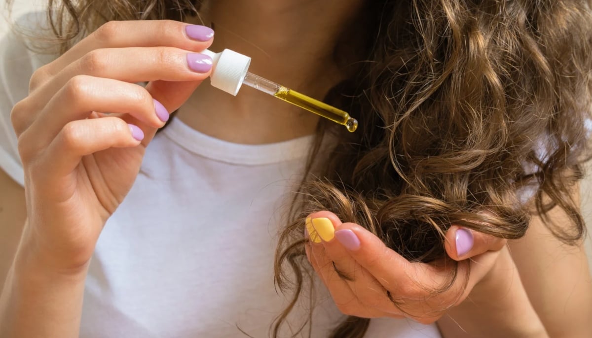 A woman is using oil on her hair. — Canva