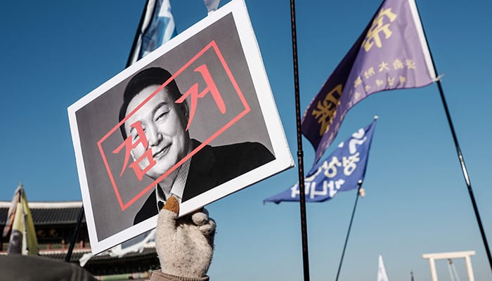 A protester walks with a portrait of impeached South Korean President Yoon Suk Yeol before a rally in Seoul on January 11, 2025. — AFP