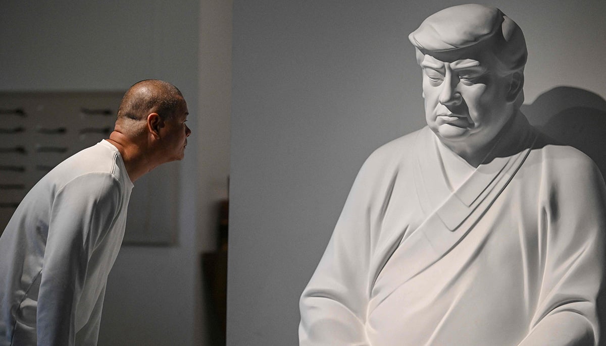 This photo taken on December 9, 2024 shows artist Hong Jinshi looking at a sculpture of US president-elect Donald Trump in a pose evoking the Buddha at his workshop in Xiamen, in southeastern Chinas Fujian province. — AFP