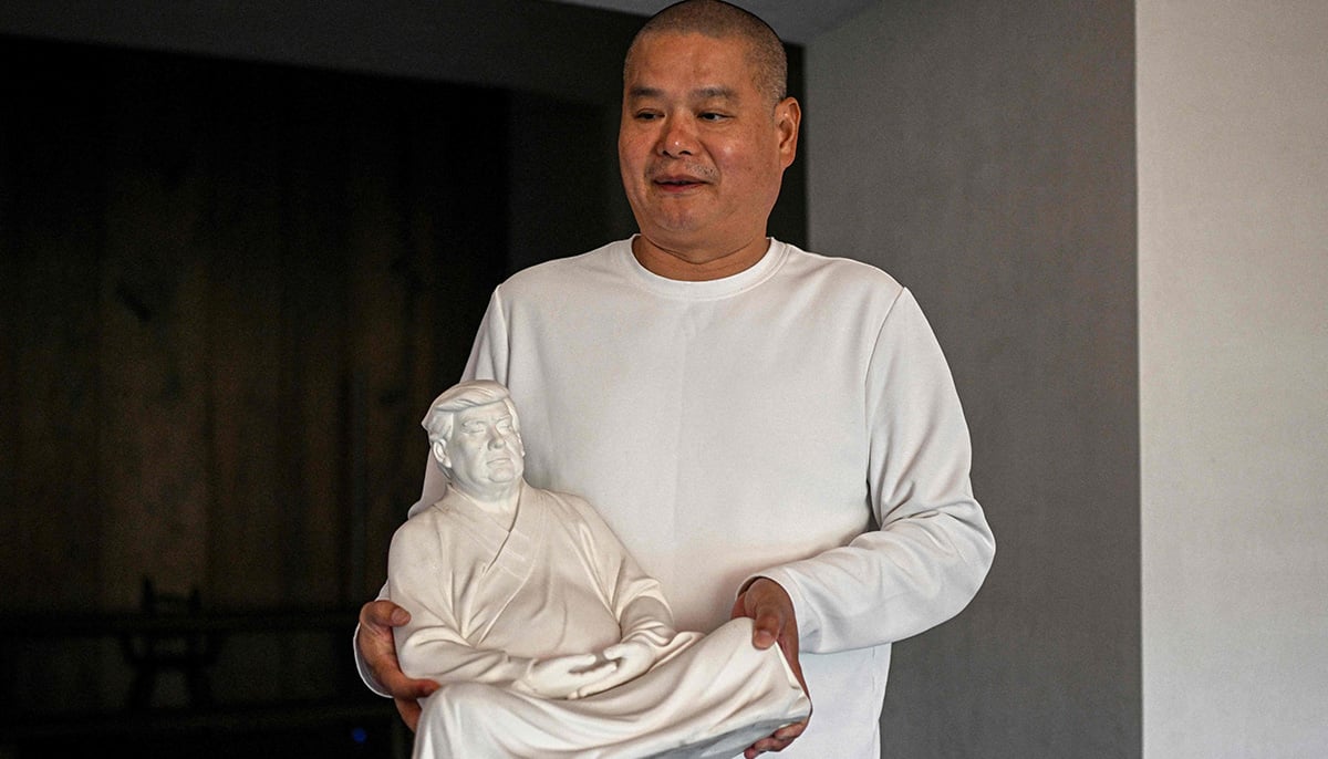 This photo taken on December 9, 2024 shows artist Hong Jinshi holding a sculpture of US president-elect Donald Trump in a pose evoking the Buddha at his workshop in Xiamen, in southeastern Chinas Fujian province. — AFP